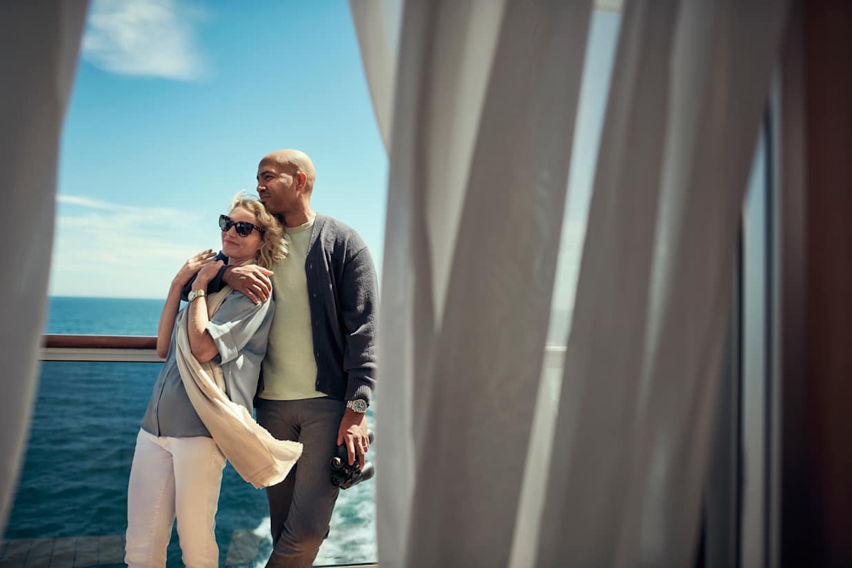 A couple standing by the railing on a Cunard cruise ship