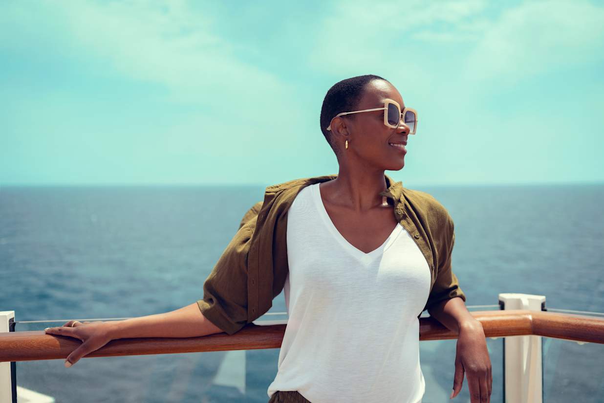 Lady smiling and posing against railing of Cunard Queen Anne