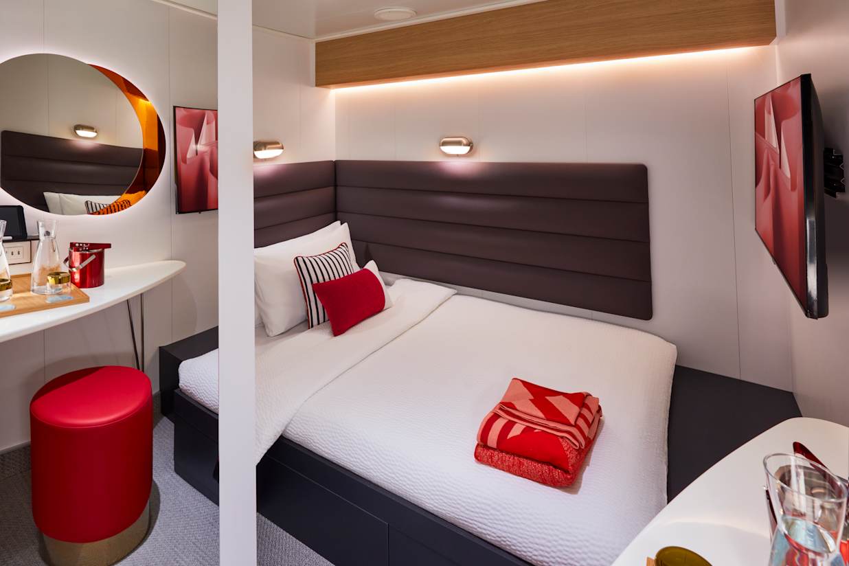 View of a bed and mirror in a Solo Insider Cabin on a Virgin Voyages cabin