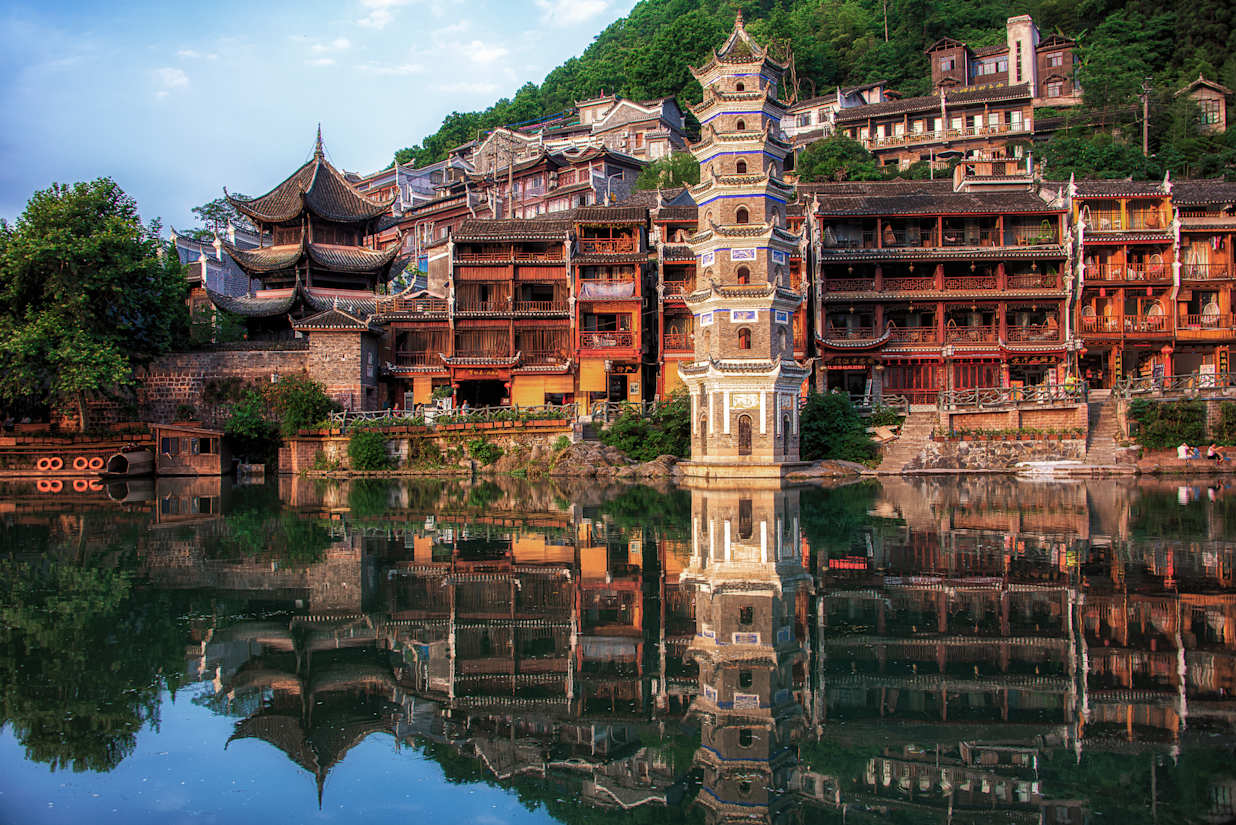 Stone pagoda and traditional stilted wooden houses along the Tuojiang River in Fenghuang Ancient Town