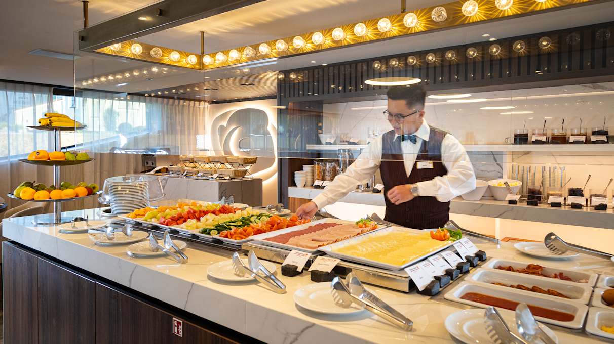 A staff member serving food onboard Capella, a Travelmarvel ship