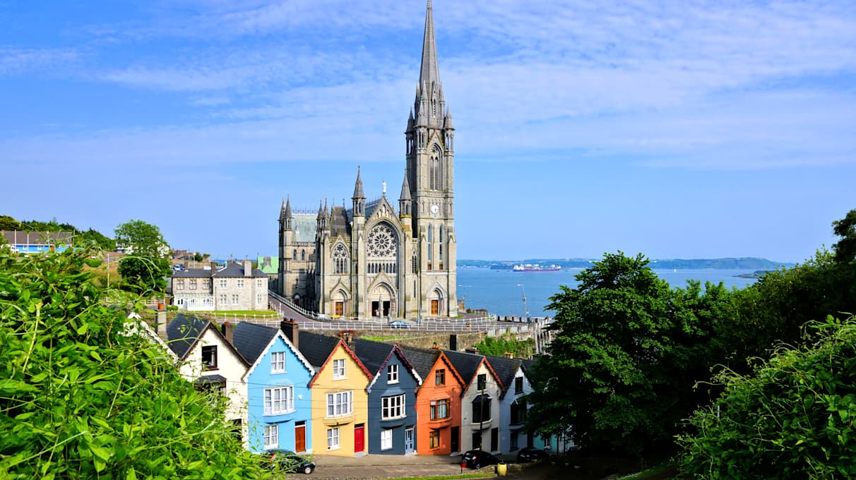 Colourful row houses with towering cathedral in background in the port town of Cobh